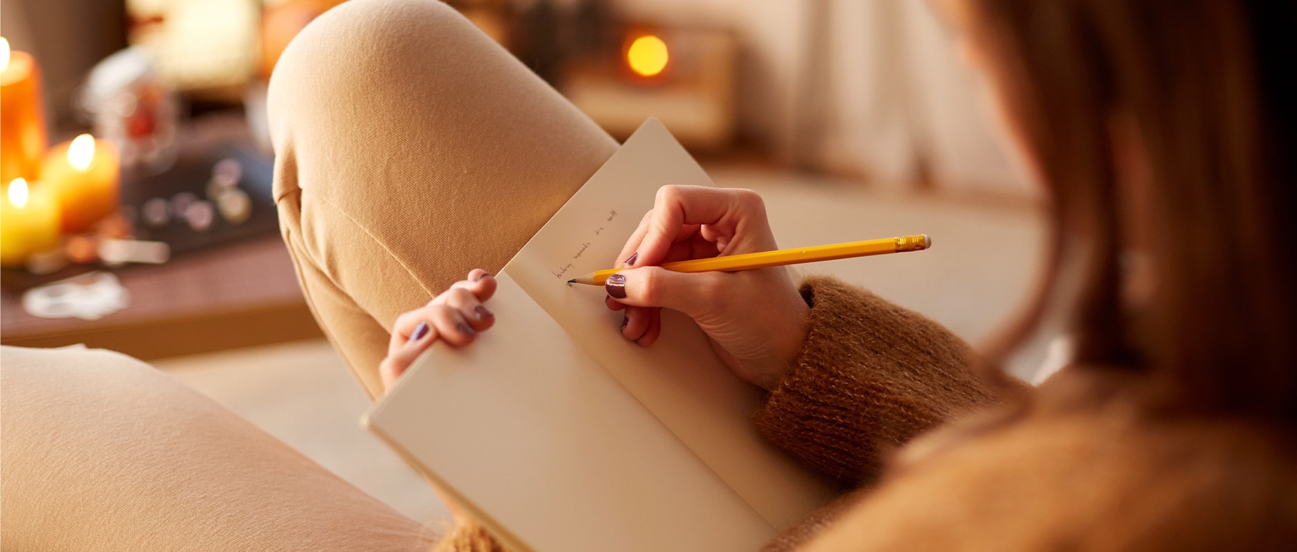 The girl is writing in a notebook with a pencil