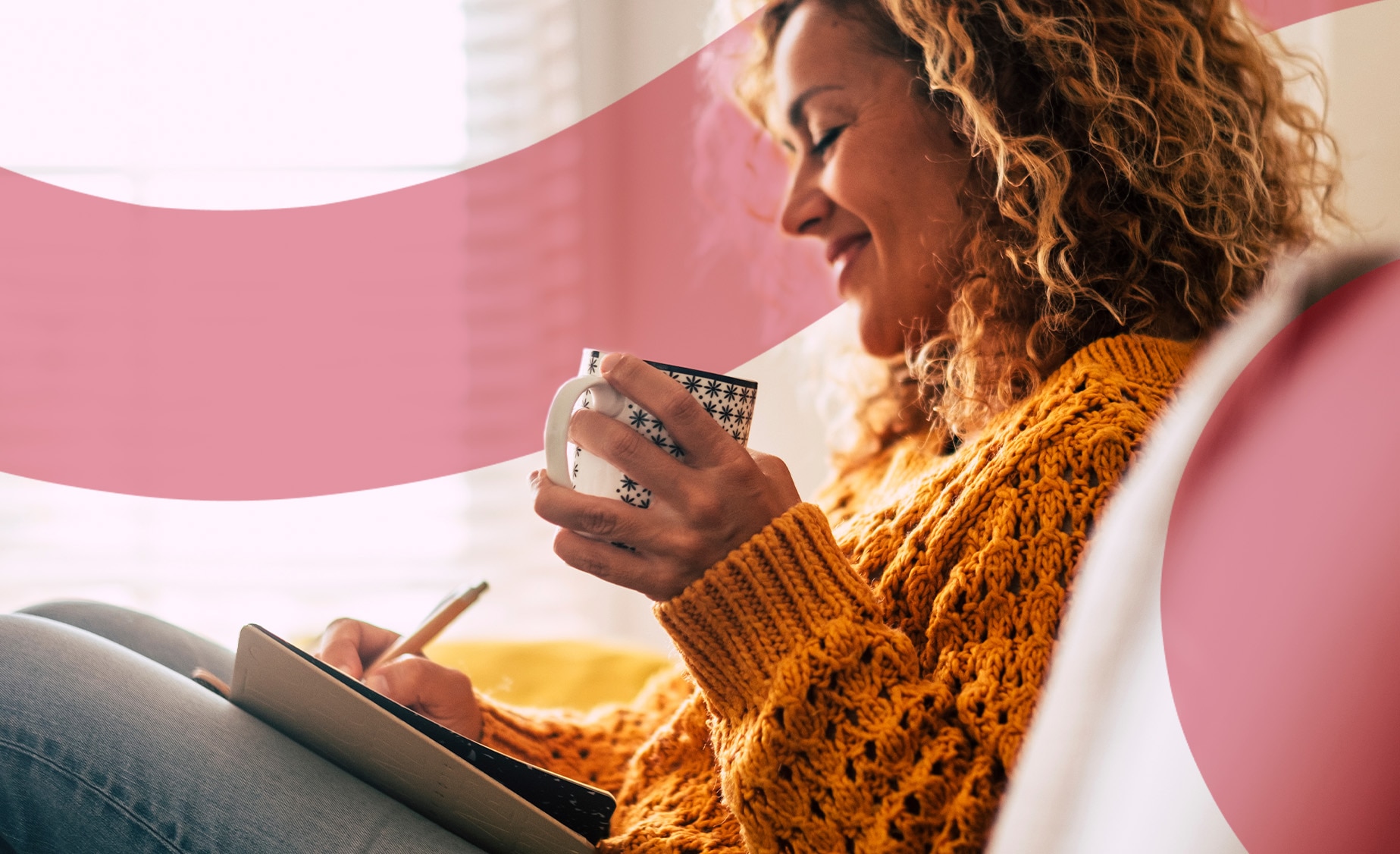 Close-up of a woman journalling in her diary with a hot drink and serene expression